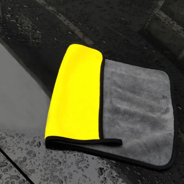מטלית מיקרופייבר לרכב צהובה ואפורה על מכונית שחורה.