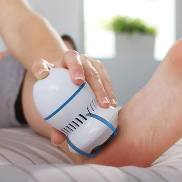 אישה משתמשת במכשיר פדיקור ביתי על רגליה.